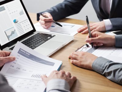 close up view of business meeting with people sitting around table reviewing financial reports